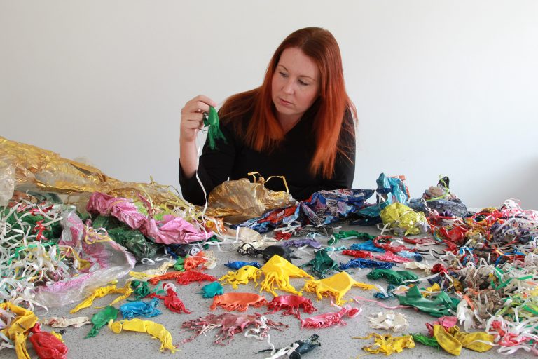 Dozens of burst balloons in jellyfish shapes sorted across a table.